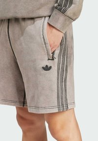 Gray cotton shorts with a textured finish, featuring black side stripes and a small embroidered logo on the left leg.