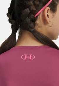 Fitted short-sleeve top in dark pink fabric, featuring a small pink logo near the neckline; smooth texture with simple design.