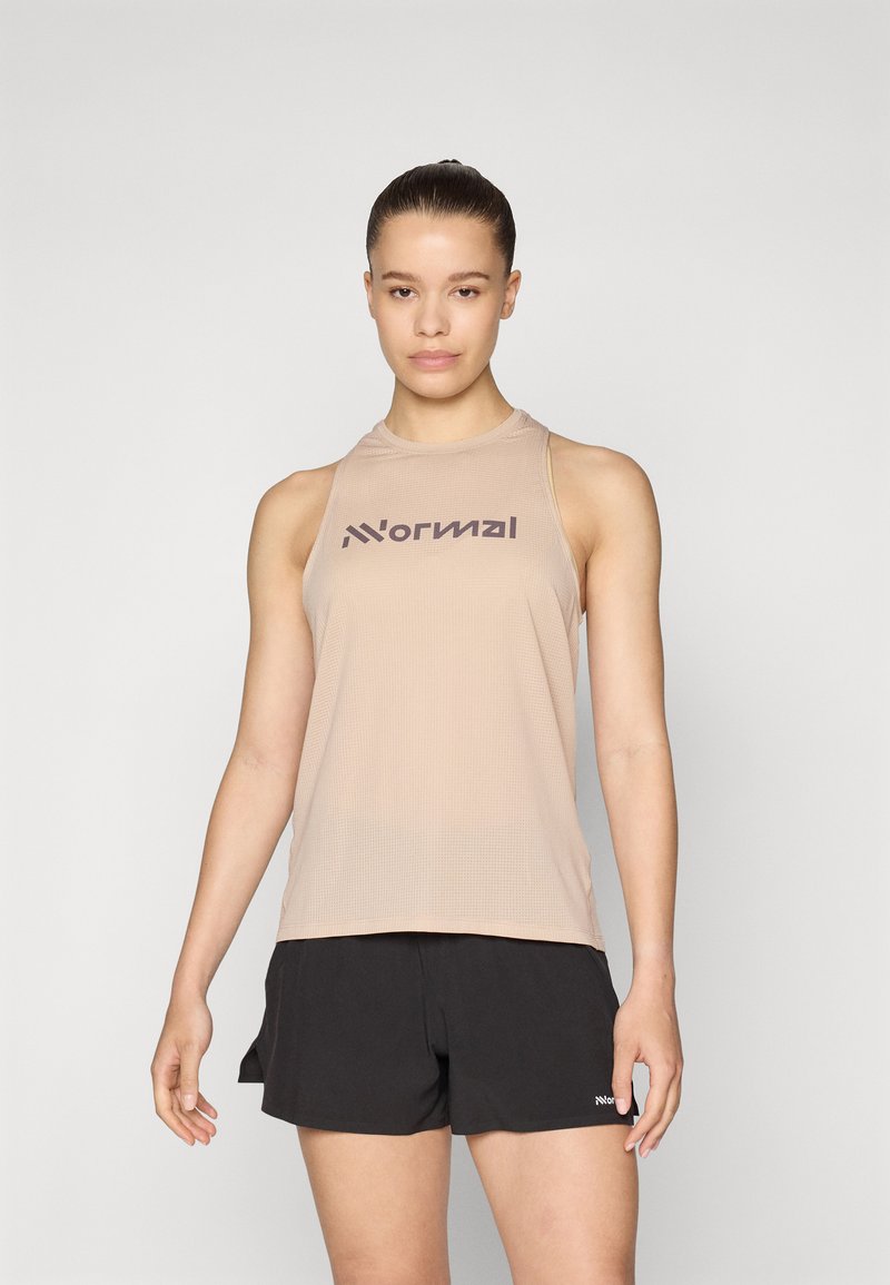 Lys beige ermeløs treningsgenser med strukturert stoff og mørk logo. Kombinert med sorte shorts, som har en subtil merkevaredetalj.