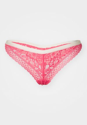 String rosa in pizzo con una cintura liscia beige, caratterizzato da motivi floreali e bordi scallopati per un tocco di dettaglio e texture.