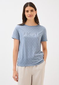 Sininen lyhythihainen t-paita, jossa on lehtikuosi ja sana "ALOHA" vaalealla värillä edessä. Valmistettu pehmeästä, kevyestä kankaasta.