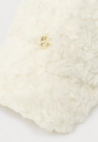 White fluffy hat with a textured surface, featuring a gold hardware logo on one side. The material appears soft and thick.