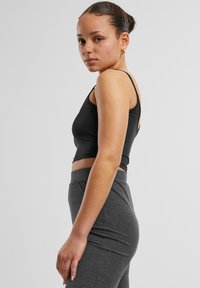 Black cropped tank top with thin straps, paired with high-waisted gray ribbed leggings. Smooth texture, fitted design, and minimalistic style.