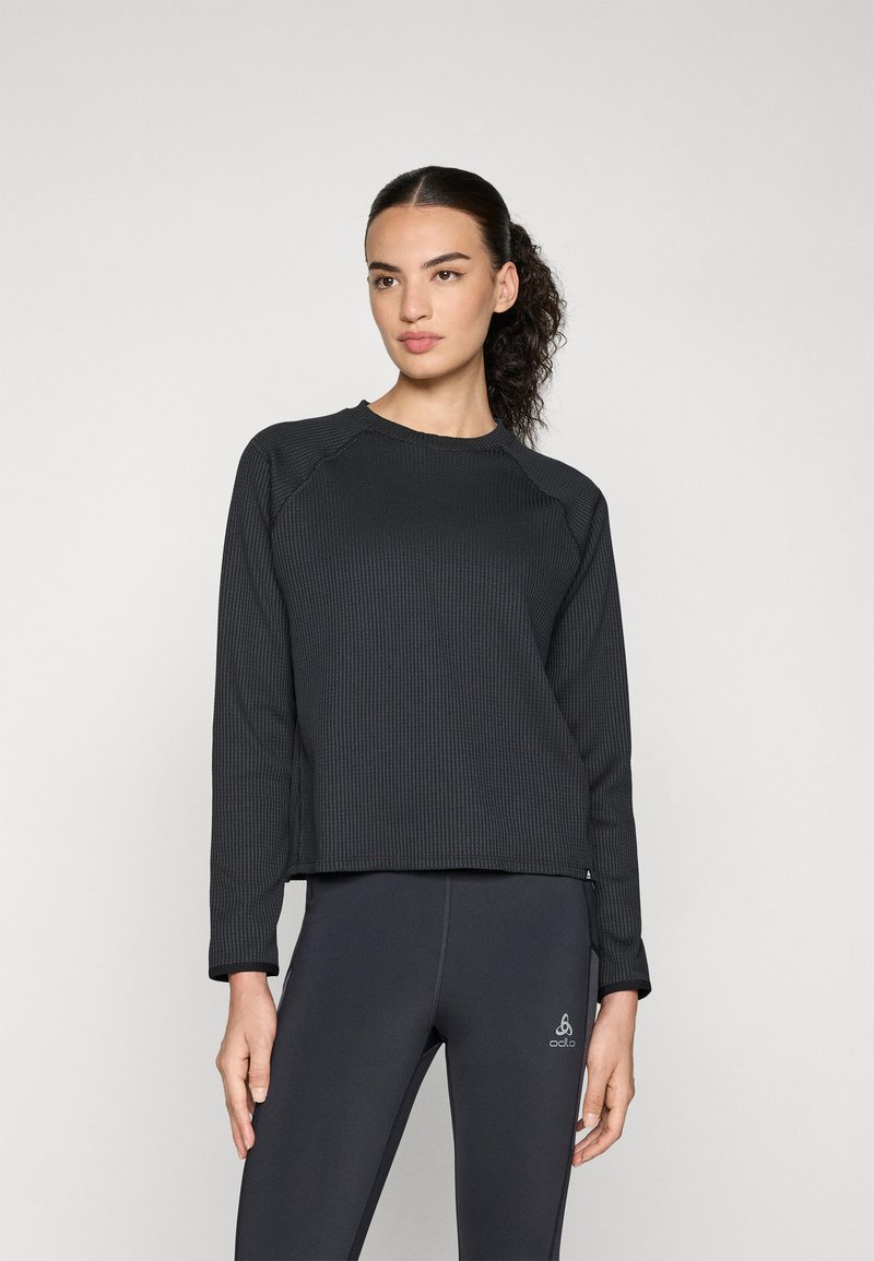 Black ribbed long-sleeve sweatshirt with a crew neckline, relaxed fit, and visible stitching. Paired with dark leggings featuring logo detail.