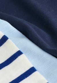 Drei Stoffmuster: Dunkelblau, Hellblau und Weiß mit blauen Streifen. Texturiertes Strickmaterial mit weichem Finish; unterschiedliche Farben sorgen für visuelles Interesse.