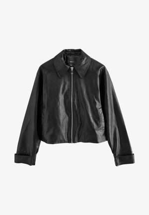 Melnā īsā ādas jaka ar izteiktu apkakli, priekšējo rāvējslēdzēja aizdari un garām piedurknēm ar plašām aprocēm. Gluda, matēta tekstūra.