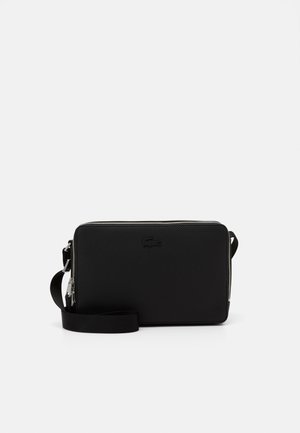 Borsa rettangolare nera in materiale testurizzato, con chiusura a zip e tracolla regolabile; presenta un logo discreto nell'angolo.