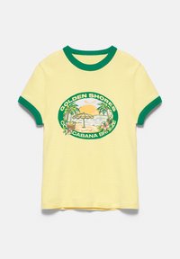 T-shirt jaune à manches courtes avec col et bords de manches verts, avec une scène de plage et le texte "Golden Shores Cabana Breeze" sur le devant.