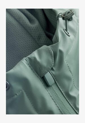Nepremokavá bunda z jemného, ľahkého materiálu v mätovo zelenej farbe; má hladkú textúru, nastaviteľné šnúrky a zosilnené švy.