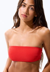 Rotes Bandeau-Oberteil mit strukturiertem, gefältetem Design. Bietet eine trägerlose Silhouette, glattes Material und eine enganliegende Form für sicheren Sitz.