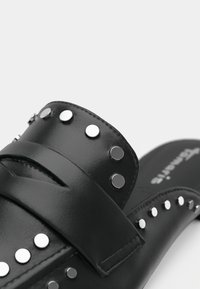 Sandales à glissière en simili cuir noir, dotées d'une large sangle ornée de clous en argent et d'une boucle ajustable. Texture lisse et semelle intérieure rembourrée.