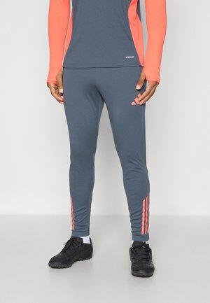 Pantalons de sport gris avec des accents rose à 3 bandes sur les côtés, fabriqués dans un matériau extensible pour le confort et la flexibilité.