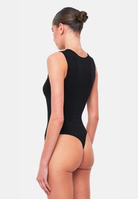 Body nero aderente con design senza maniche, collo alto e schiena a perizoma. Texture liscia, offre una copertura totale sul davanti.