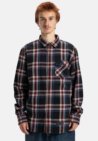 Czarna, czerwona i niebieska koszula flanelowa w kratę z kołnierzykiem zapinanym na guziki, kieszonką na piersi i długimi rękawami. Miękka struktura, klasyczny krój.