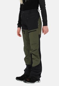 Spodnie narciarskie w ciemnozielonym i czarnym kolorze, z wieloma kieszeniami na zamki, regulowanym pasem oraz zwężanym krojem zapewniającym swobodę ruchów.