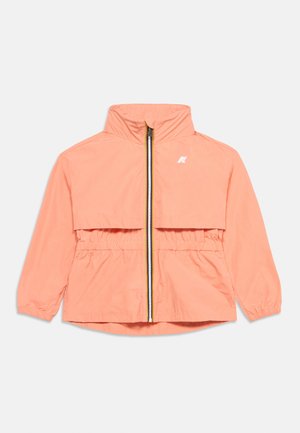 Veste zippée corail clair avec col haut, poignets et taille élastiques, arborant un petit logo blanc sur le côté gauche de la poitrine.