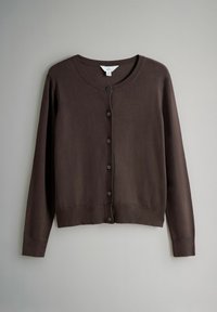 Tumši brūns, garām piedurknēm, ar pogām, apaļa kakla izgriezuma kardigans, kurš karājas pret vienveidīgu gaiši pelēku fonu.