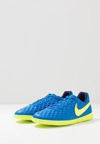 Zapatillas deportivas azules con un superior texturizado, acentos amarillos, diseño de cordones y una suela flexible. Presenta un patrón de diamantes en el material.
