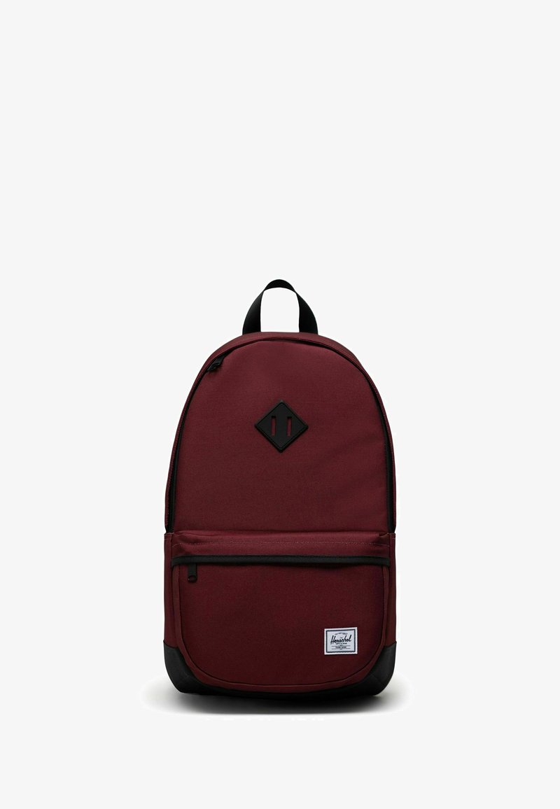 Sac à dos en tissu bordeaux avec un écusson en forme de losange noir, une poche avant zippée et un panneau inférieur noir. Comprend des bretelles réglables et une poignée supérieure.