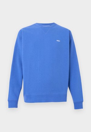 Modré tričko s dlouhým rukávem vyrobené z bavlněné směsi s žebrovanými manžetami a lemem. Na hrudi se nachází malý bílý nápis "OBEY". Design s kulatým výstřihem.