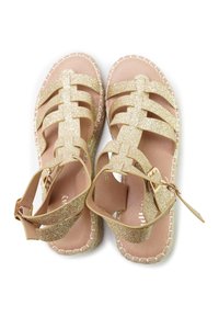 Gold glitter sandals with crisscross straps and ankle buckle, featuring a natural tan insole and jute-wrapped sole. Textured finish.