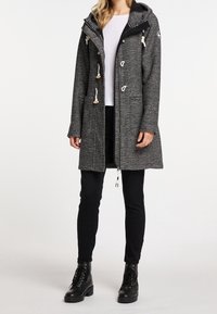 Grå, huva lång kappa med knappar framtill, dragsko-detaljer, sidofickor och en texturerad tygfinish. Matchad med svarta byxor och stövlar.