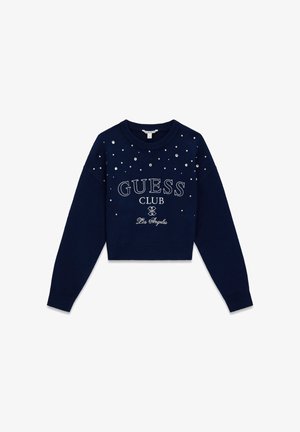 Pull court bleu marine avec col rond, orné de strass clairs dispersés. "GUESS CLUB Los Angeles" imprimé en blanc.