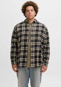 Sort/hvid ternet flannel skjorte med beige detaljer, med knaplukning foran og en afslappet pasform, båret over en olivengrøn skjorte.