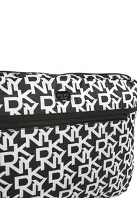 Bolso en blanco y negro con un patrón repetido de letras grandes. Tela texturizada con un compartimento con cremallera y una etiqueta de marca.