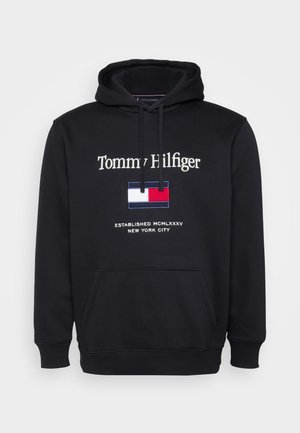 Juodas džemperis su kapišonu ir kišene priekyje. Ant priekio yra "Tommy Hilfiger" logotipas ir išsiuvinėtas vėliavos dizainas raudonos, baltos ir mėlynos spalvų.