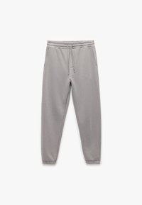 Grijze sweatpants gemaakt van zachte stof met een elastische tailleband en een verstelbaar trekkoord, voorzien van twee zijzakken en taps toelopende broekspijpen.