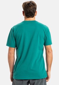 Tyrkysové bavlněné tričko s kulatým výstřihem, krátkými rukávy a volným střihem, s hladkou strukturou a bez viditelných vzorů.