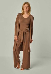 Braunes Loungewear-Set mit einem gerippten Tanktop und weiten Hosen mit einem Bindeband am Bund sowie einem offen fallenden langen Cardigan. Weiche Textur.
