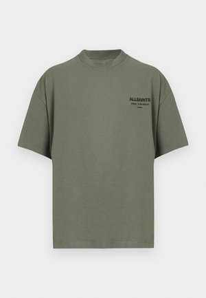 Olívazöld pamut póló kerek nyakkivágással, rövid ujjakkal, és egy kis nyomott logóval a mellkason. Simább textúra, kényelmes szabás.