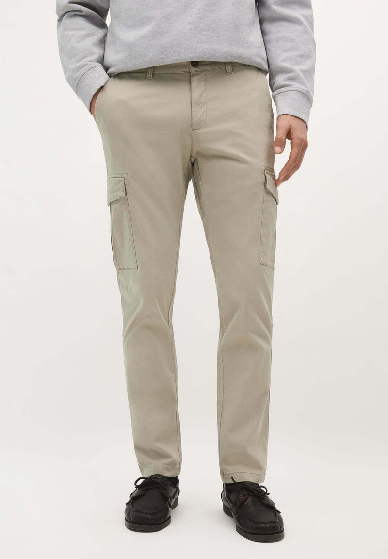 Pantalons cargo beiges avec poches latérales, fabriqués en coton. Le design présente une coupe droite, des passants de ceinture et une fermeture à bouton.