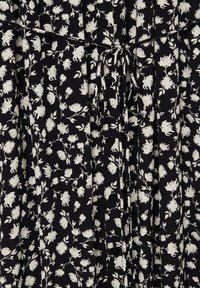 Schwarzes Kleid mit weißem Blumenmuster, mit gebundenem Taillenzug, Knöpfen vorne und plissierter Textur.