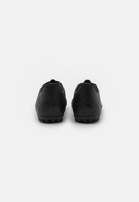 Scarpe sportive nere con tomaia in sintetico liscio, tacco arrotondato e suola testurizzata. Presentano un marchio discreto sul retro e sui lati laterali.