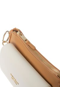 Farbig unterteilte Reißverschlusstasche in Beige und Weiß mit goldfarbener Hardware. Texturierte Oberfläche mit Logodetail im weißen Bereich.