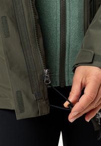 Giacca verde scuro con chiusura zip, caratterizzata da uno strato interno texturizzato. Orlo con cordino regolabile e zip a contrasto.