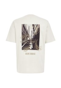 Light beige cotton T-shirt featuring a black and white urban photo print, decorative paisley designs, and "BLUE RIDGE" text in gold.