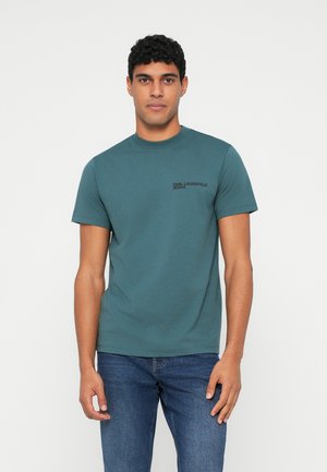 Dark teal short-sleeve t-shirt with a crew neckline. Features a small black printed logo on the left chest. Made of soft cotton material.