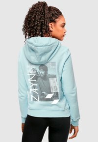 Világoskék kapucnis sweatshirt, puha anyagból, nagy grafikai nyomattal a háton, szöveges és képi elemekkel. Rászedett mandzsetták és derék.