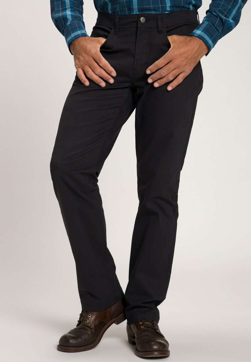 Zwarte chino's met een slanke, op maat gemaakte pasvorm. Voorzien van zijzakken, een rits met gulp en ceintuurlussen. Gedragen met bruin leren schoenen.