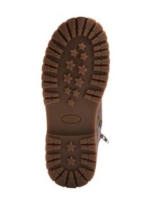 Suela de una bota marrón con profundas ranuras y patrones en forma de estrella diseñados para tracción y durabilidad.