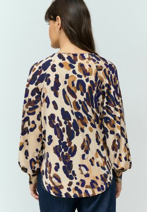Blouse à imprimé léopard en beige, avec des taches violettes et brunes. Manches longues en forme de ballon et col rond. Texture de tissu lisse.