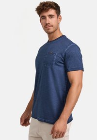 Marineblå t-shirt med korte ærmer i blødt stof, med en lomme på venstre bryst og rund halsudskæring, samt en afslappet pasform.