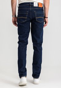 Granatowe dżinsy z dopasowanym krojem, z pomarańczowym przeszyciem, dwoma tylnymi kieszeniami z ukośnymi szwami oraz metką z logo na pasku talii.