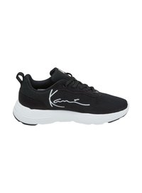 Chaussure de sport noire avec une tige en mesh, semelle blanche et un détail de signature bien visible sur le côté. Elle présente une finition texturée et un design à lacets.