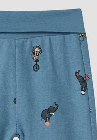 Blauwe katoenen legging met geborduurde circusdieren. Het ontwerp bevat een leeuw op een eenwieler en olifanten met ballen. Zachte textuur.