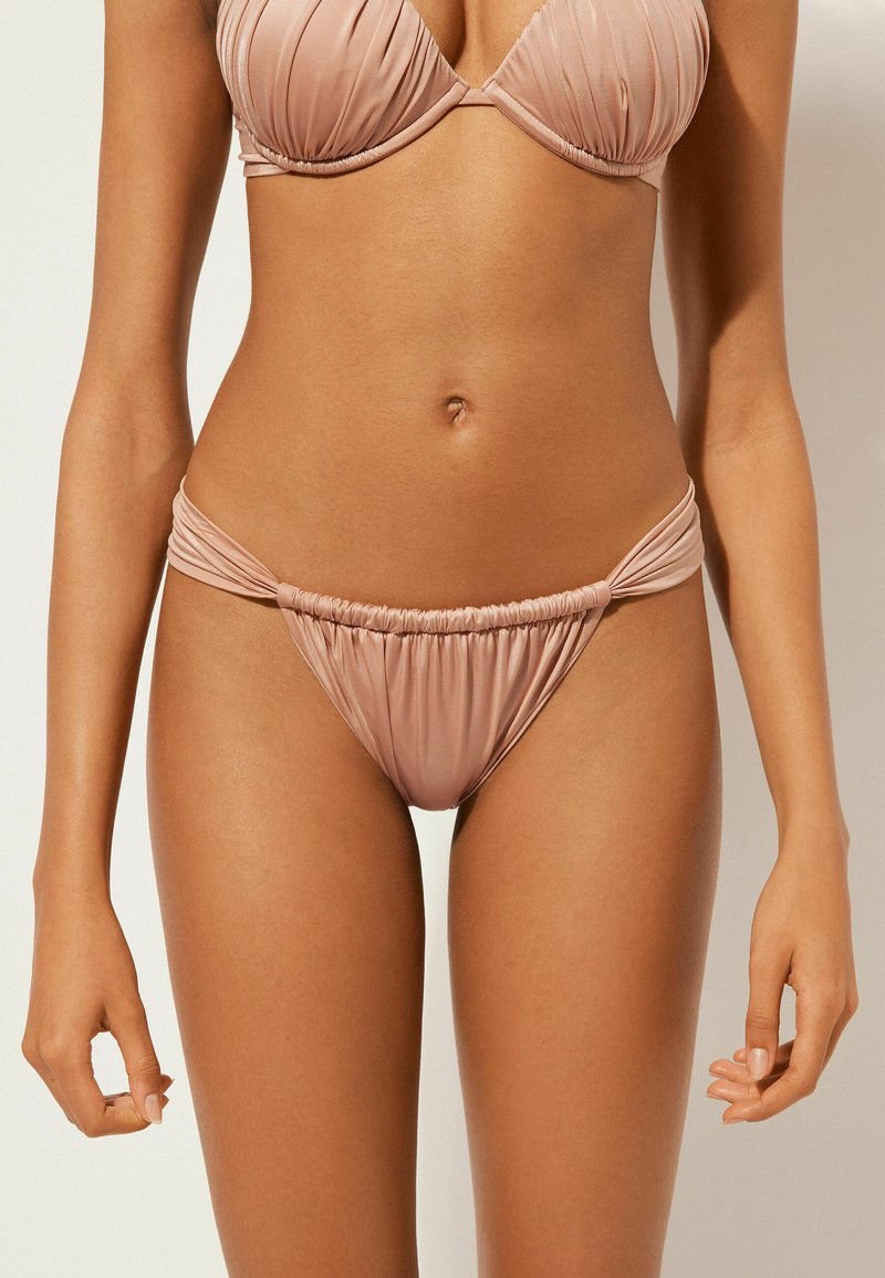 Hellrosa Bikini-Oberteil mit gerafftem Stoff und passendem, niedrig sitzendem Unterteil mit seitlicher Raffung und elastischem Bund. Glatte Textur.